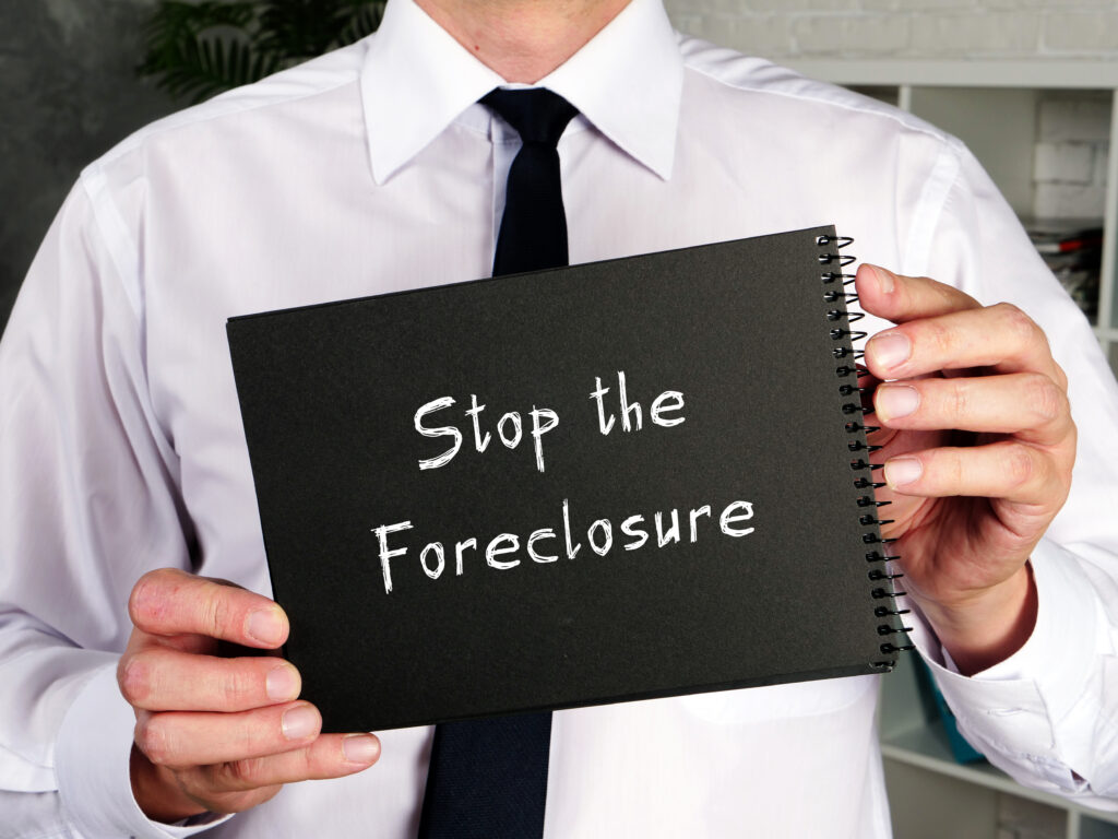 A man holds a sign reading stop the foreclosure.