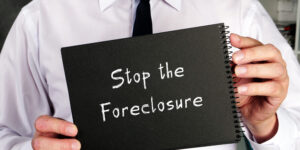 A man holds a sign reading stop the foreclosure.
